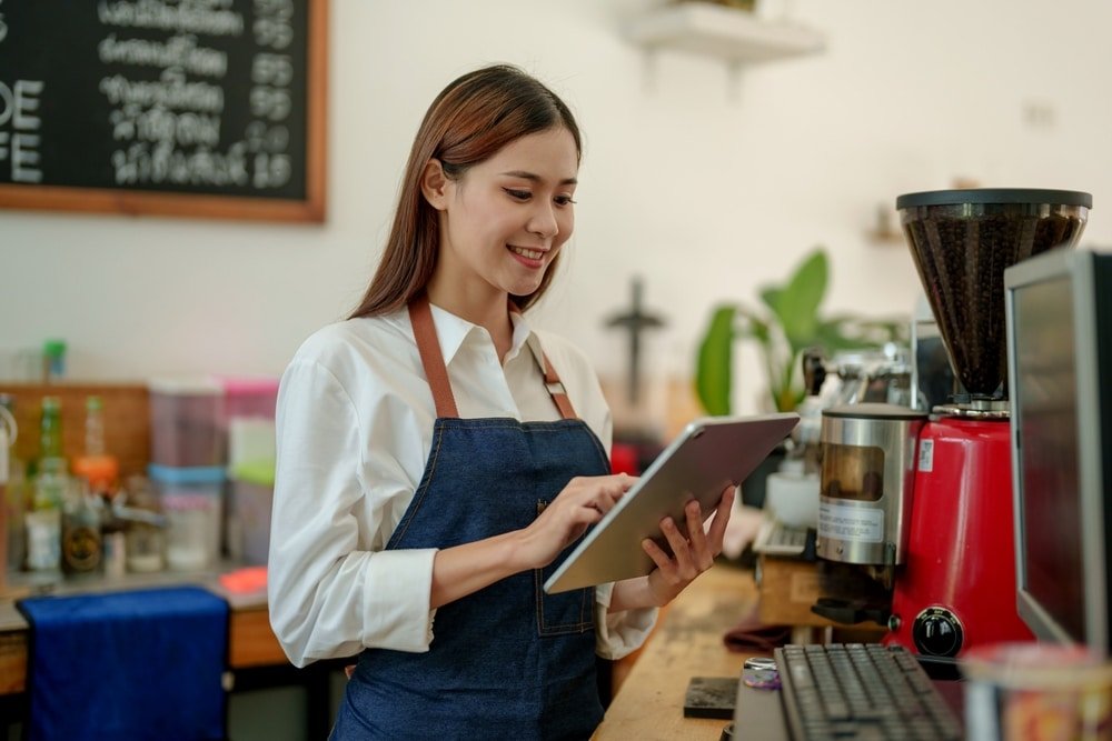 Smiling,Asian,Woman,Coffee,Shop,Owner,Standing,Holding,Tablet,And